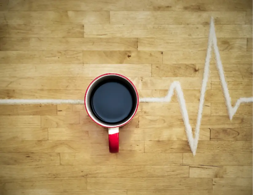 Proven workout motivation strategy #1: Caffeinate. A cup of coffee with a trail of white sugar depicting a heartbeat.