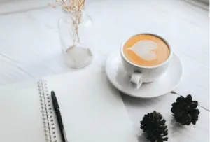 cup of coffee with journal - caffeine is known to suppress appetite and aid in fat loss