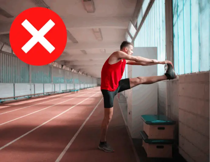 the Problem with stretching showing man stretching hamstrings standing on indoor track