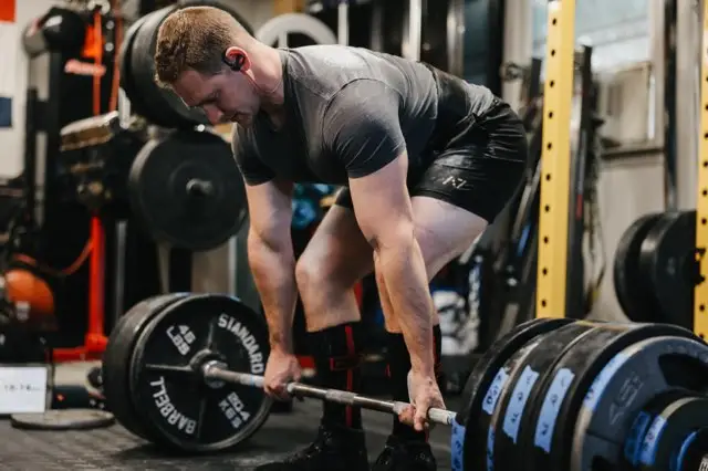 man preparing to deadlift heavy barbell fueled by athlete diet trusted by team, power and strength athletes