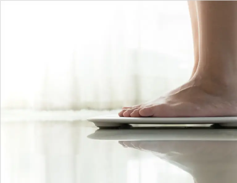 person stepping on a scale to check holiday weight gain